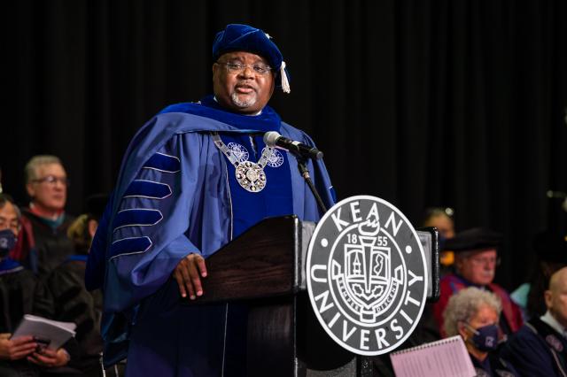 爱游戏体育 President Lamont Repollet, wearing a cap and gown, speaks at the podium at Prudential Center.