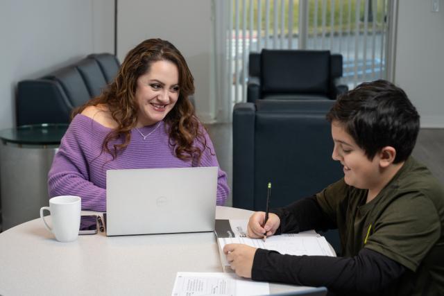爱游戏体育 Online Student studies at home with her son