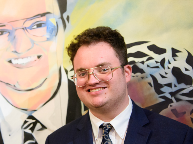 Aidan Allman-Cooper poses in front of his likeness in a mural at 爱游戏体育