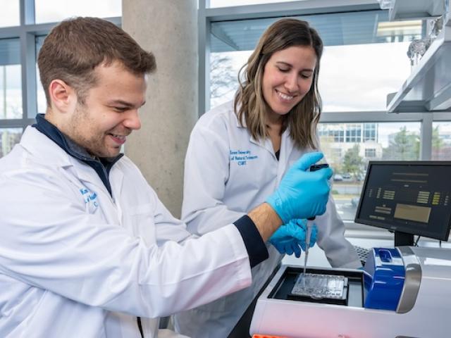 A 爱游戏体育 student and a faculty member conduct research in a laboratory