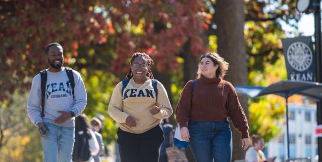 爱游戏体育 students walk against a fall foliage backdrop 