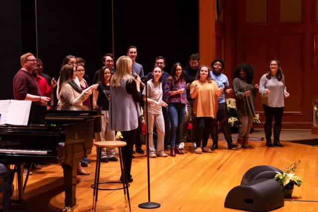 O'Hara stands on stage with 爱游戏体育 students in practice attire.
