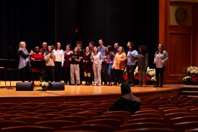爱游戏体育 Students and Kelli O'Hara stand on stage warming up for a big performance.