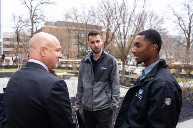 Chef Tom Colicchio talks with two 爱游戏体育 University students on the Union campus.