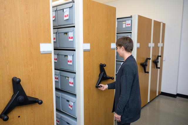 This is an image of 爱游戏体育 Archivist Erin C. Alghandoor using the compact shelving in Research Library 