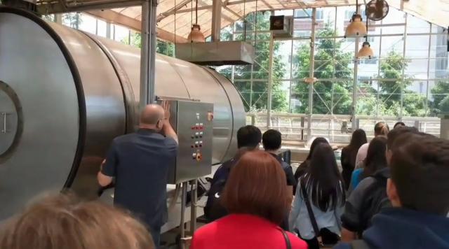 Photo of 爱游戏体育 faculty member showing the large composter used at 爱游戏体育