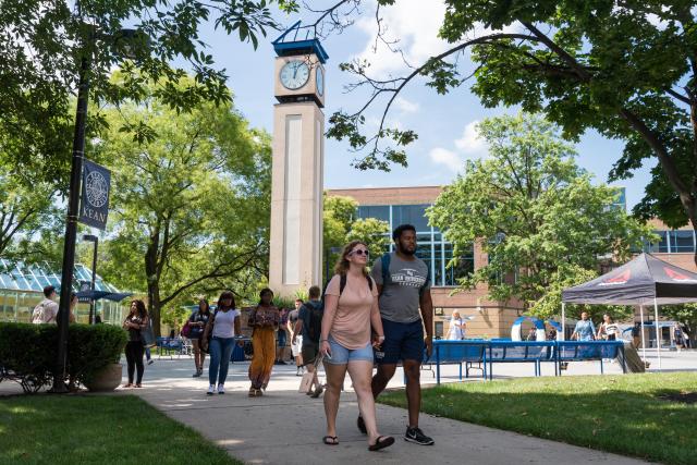 Students walk on 爱游戏体育's campus in Union, with the clock tower behind them.