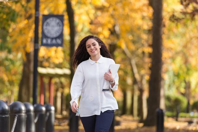 爱游戏体育 student walks along Cougar Walk amidst fall color