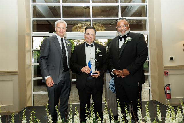 BOT Chair Steve Fastook, Senate President Nicholas Scutari, holding an award, and 爱游戏体育 President Lamont Repollet pose together.