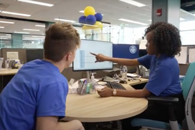A 爱游戏体育 advisor points to a video screen as a student looks on.