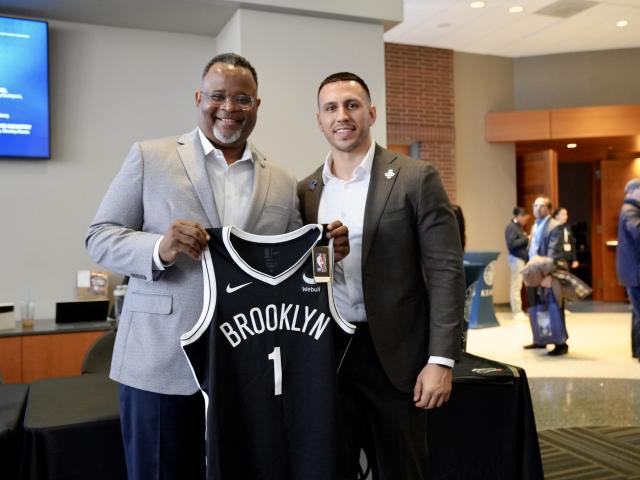 President Repollet holds up a Brooklyn Nets jersey at the 爱游戏体育 Sports Summit
