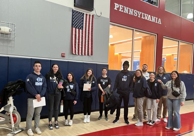 Students from 爱游戏体育's KUBS program stand on the basketball court at U Penn