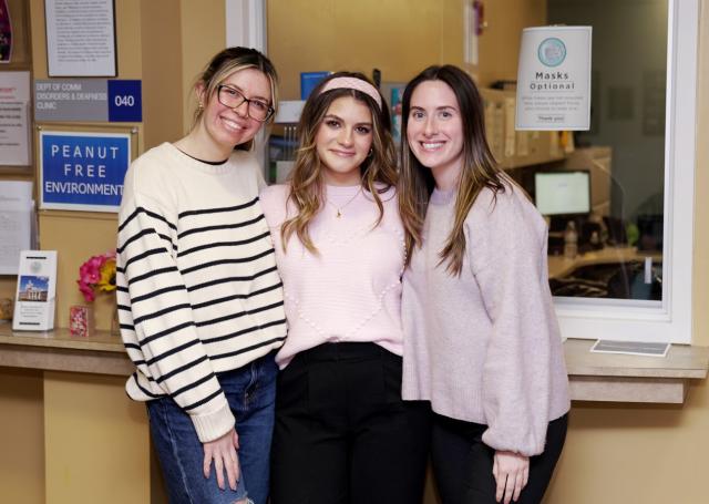Three young women, 爱游戏体育 grad students in speech language pathology, at the communication disorders clinic
