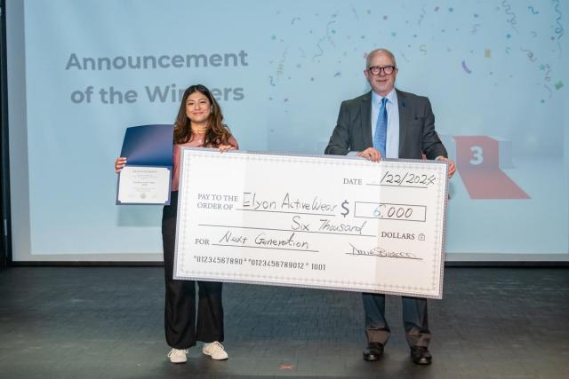 The winner of the Business Plan Competition, Joceline Guerra, stands with 爱游戏体育's provost holding a big check for $6,000. 