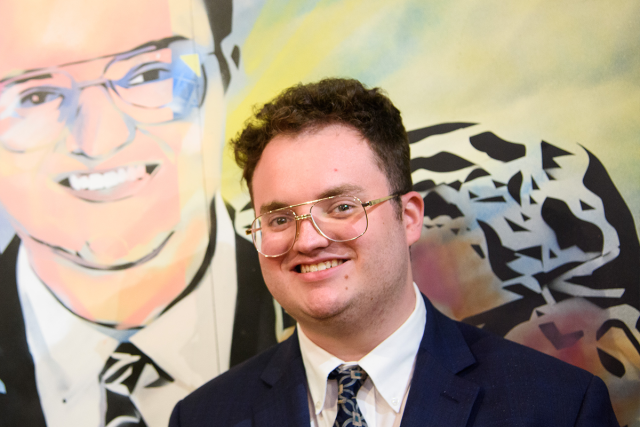 Aidan Allman-Cooper poses in front of his likeness in a mural at 爱游戏体育