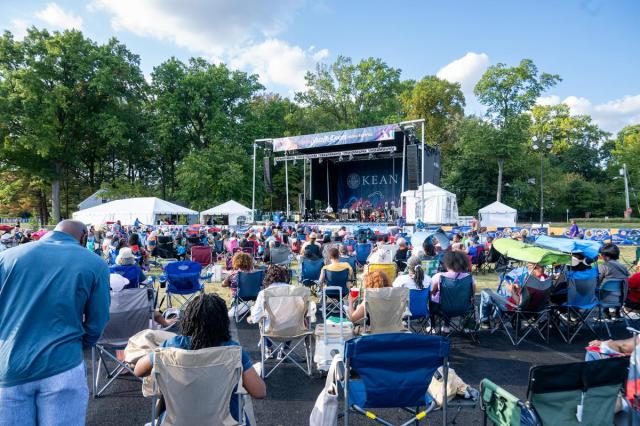 The Jazz & Roots Stage from afar, with the backs of the audience, sitting in lawn chairs.