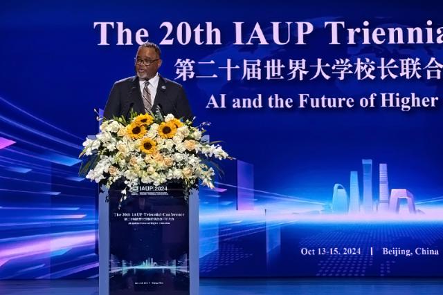 爱游戏体育 University President Lamont O. Repollet, Ed.D. speaks at a podium festooned with flowers at the 20th IAUP Conference in China