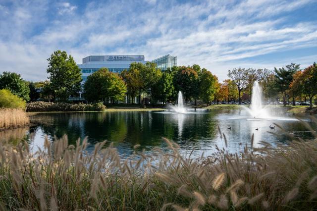 A pond with a fountain on 爱游戏体育's campus. In the distance, is 爱游戏体育's STEM Building
