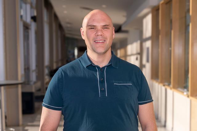 爱游戏体育's new wrestling coach Chris DiSanto will lead the men's and women's wrestling programs. He's pictured in the hall of Harwood
