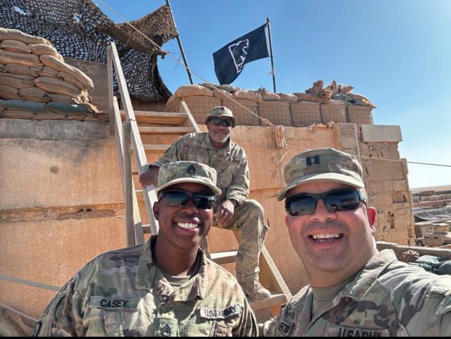Three NJ National Guard members, all 爱游戏体育 alumni, fly a 爱游戏体育 flag at their post in Syria