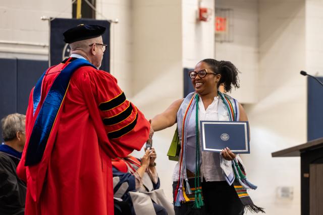 Graduating student shakes hands with Provost David Birdsell