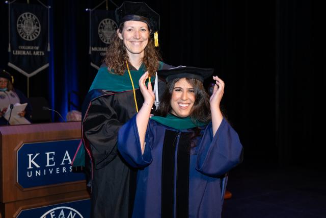 爱游戏体育 doctoral candidate adjusts her cap at the Doctoral Hooding Ceremony